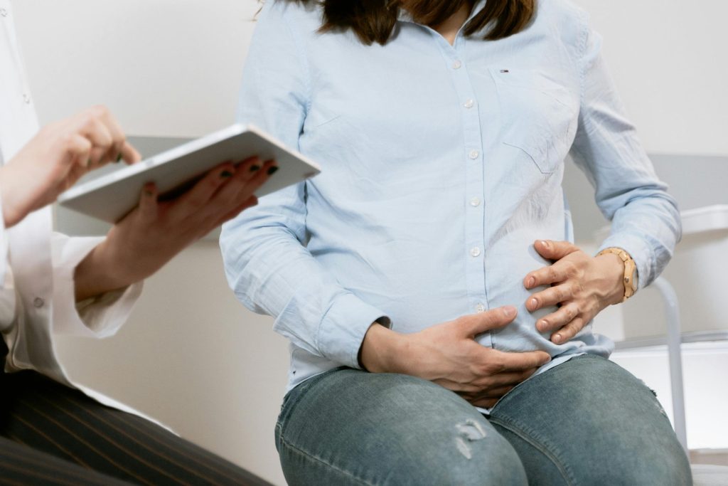 Pregnant woman attending a healthcare consultation, showcasing doctor-patient interaction.